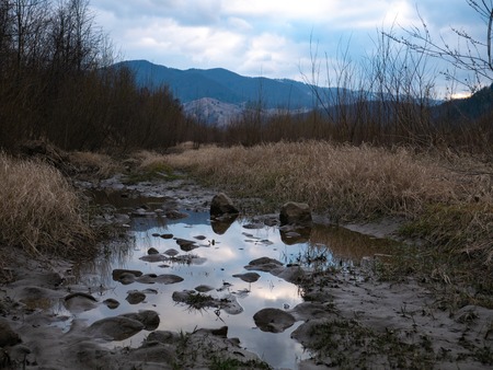 brook grass against mountains and clouds sky