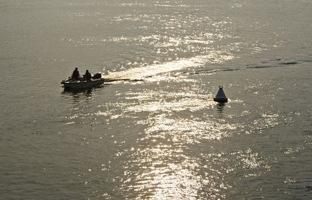 People riding a motor boat along the river near white buoy at sunset の写真素材