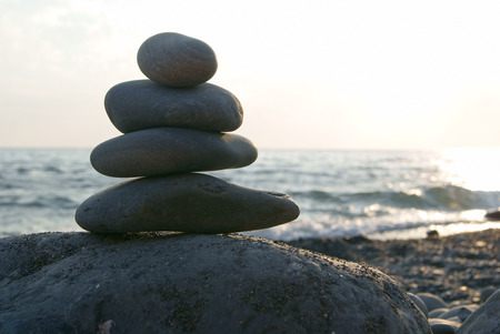 Stones pyramid on beach symbolizing zen, harmony, balance at sunset over the oceanの写真素材