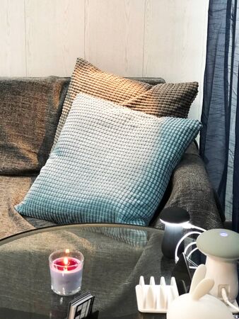Two pillows on the sofa as waiting zone in studio with candle, phone chargers and lampの写真素材