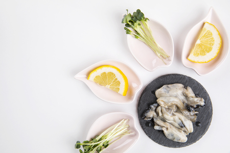 fresh oysters in a black plate on white background.の写真素材
