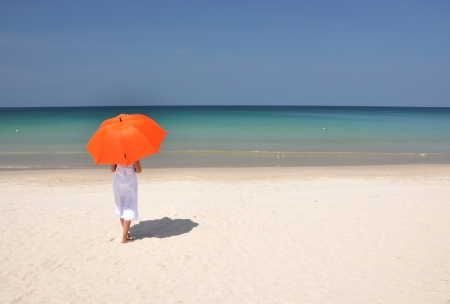 Girl with an orange umbrella on the sandy beachの写真素材