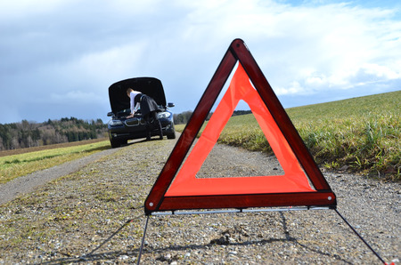 Girl, broken car and warning triangle の写真素材
