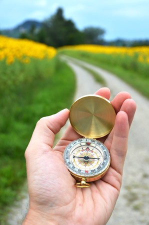 Compass in the hand against rural roadの写真素材