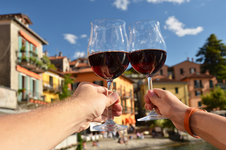 Two wineglasses in the hands. Varenna town at the lake Como, Italyの写真素材