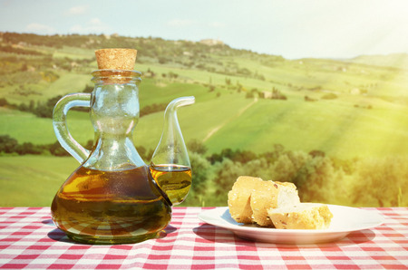 Olive oil and bread on the table against Tuscan landscape. Italyの写真素材