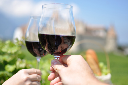 Two hands holding wineglasses against Chateau d'Aigle, Switzerlandの写真素材