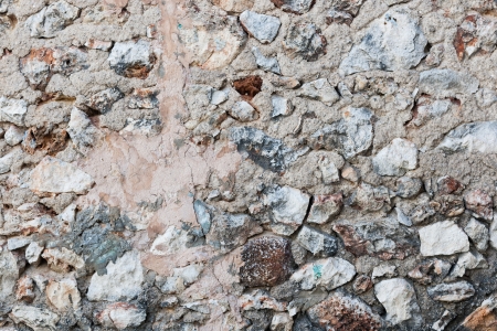 Background texture of a rock wall with rough uncut stones and pebbles of all shapes and sizes arranged randomlyの写真素材