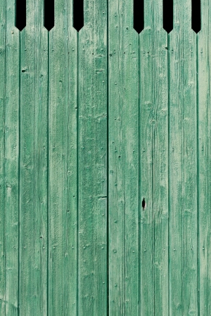 Background texture of old green painted weathered wooden planks forming an exterior cladding on a wall of a building or a fenceの写真素材