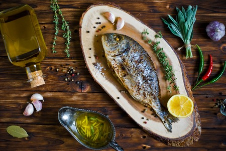 baked dorado \ dorada fish on a dark wooden background, top viewの写真素材