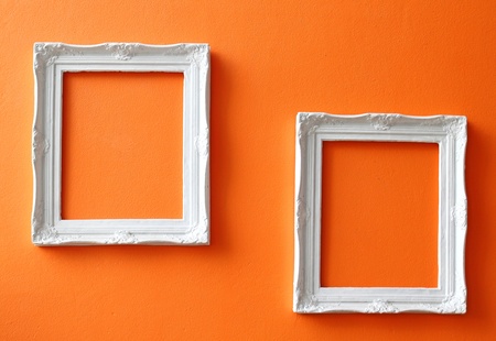 Two white vintage frames on orange wall 