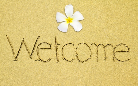 Welcome written on sand with frangipani at the beachの写真素材