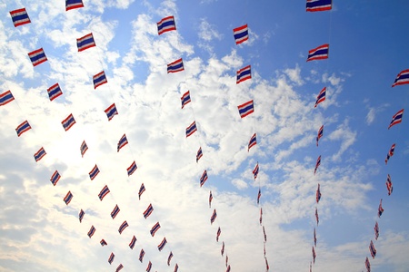 waving Thai flags hanging on a blue sky の写真素材