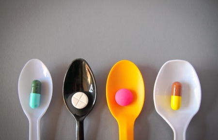 four spoons with different pills with copy spaceの写真素材