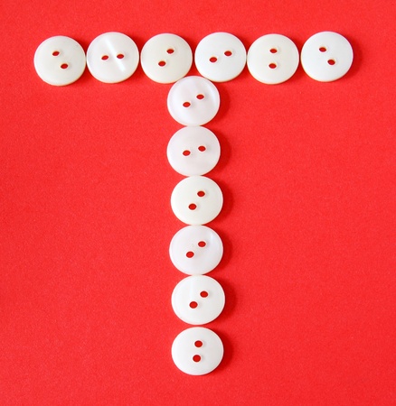 Letter "T" from buttons on a red backgroundの写真素材