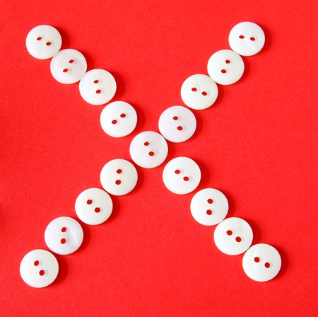 Letter "X" from buttons on a red backgroundの写真素材
