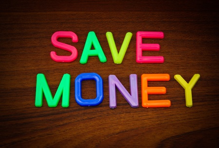 Save money in colorful toy letters on wood backgroundの写真素材