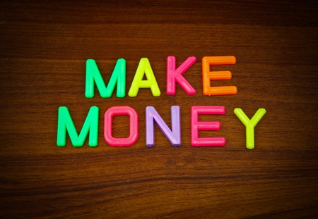 Make money in colorful toy letters on wood backgroundの写真素材