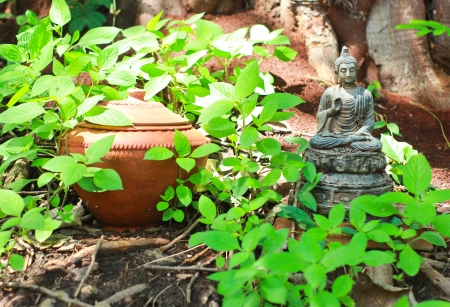 Buddha statue with pot in gardenの写真素材