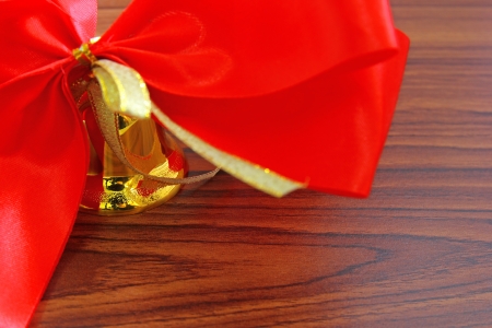 Bell with red ribbon over wooden background の写真素材
