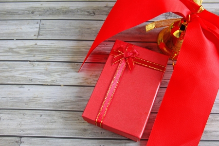 Gift box and red ribbon over wooden background の写真素材