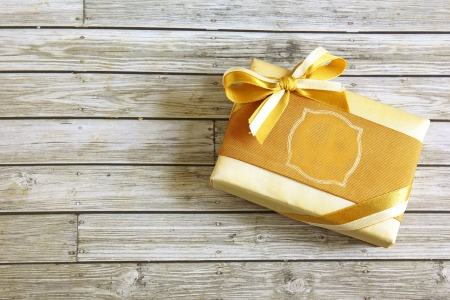 Gold present box on wooden background の写真素材