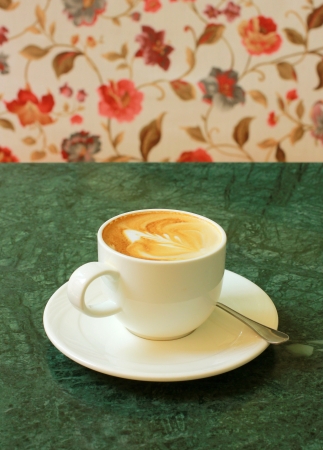 Cappuccino or latte coffee on table with flower chairの写真素材