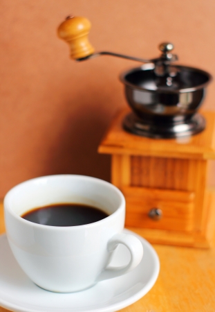 Cup of hot coffee with coffee grinder and beans の写真素材