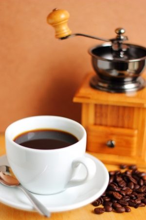 Cup of hot coffee with coffee grinder and beans の写真素材