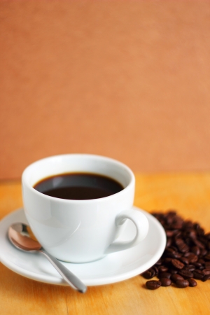 White cup of coffee with coffee beans and spoonの写真素材