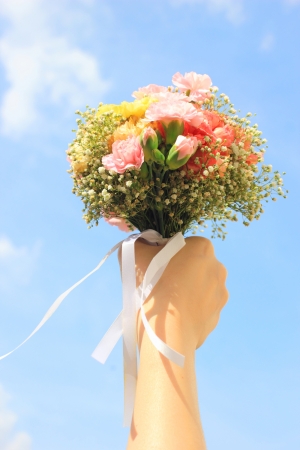 Bouquet of flower in hand and blue sky の写真素材