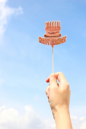 Hand holding happy birthday tag with blue skyの写真素材
