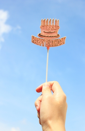 Hand holding happy birthday tag with blue skyの写真素材