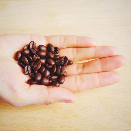 Close up of a hand full of coffee beans with retro filter effectの写真素材