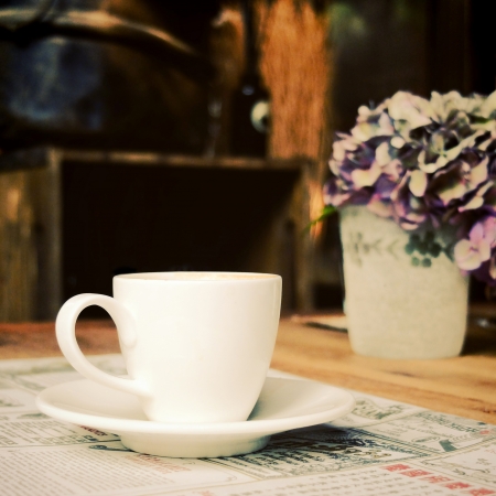 Cup of coffee with newspaper at coffee shop, retro filter effectの写真素材