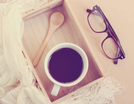 Eyeglasses and black coffee on wooden tray, retro filter effectの写真素材