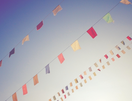 Colorful bunting flags on blue sky with retro filter effectの写真素材