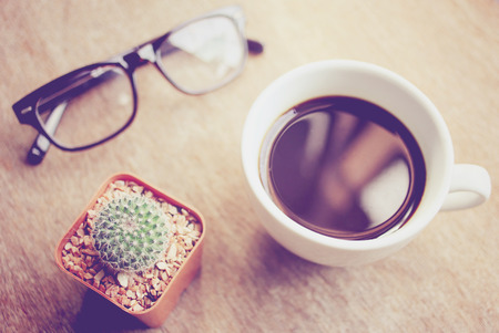 Black coffee and eyeglasses with cactus, retro filter effectの写真素材