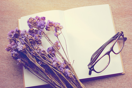 Blank notebook and dried statice flowers with eyeglasses, retro filter effectの写真素材