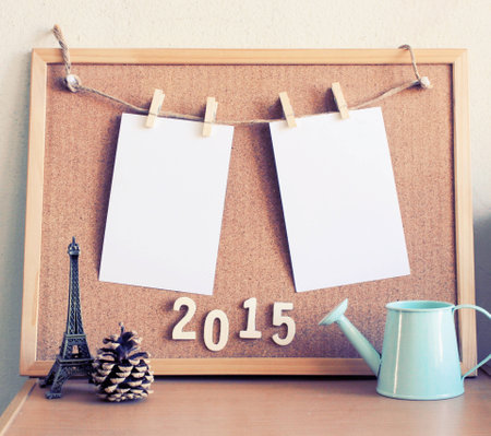 Blank note paper hanging on a rope over cork board with model decoration on the table, retro filter effectの写真素材