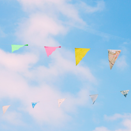 Colorful bunting flags on blue sky with retro filter effectの写真素材