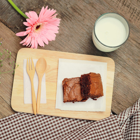 Tasty brownies with glass of milk and flower, retro filter effectの写真素材