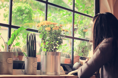 Woman using smartphone in coffee shop with retro filter effectの写真素材