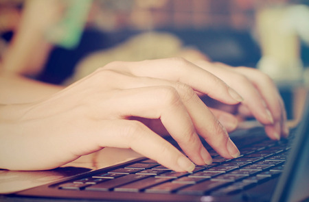 Female hands typing on laptop with retro filter effectの写真素材