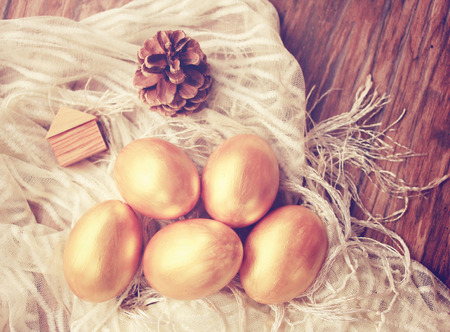 Gold easter eggs and decorated on wood background with retro filter effectの写真素材