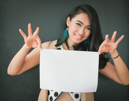 Smile asian young woman holding blank white sheet of paperの写真素材