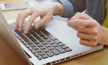 Woman's hands holding credit card and using laptop, online shopping conceptの写真素材