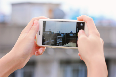 Close up of girl?s hands taking picture with smartphone on city