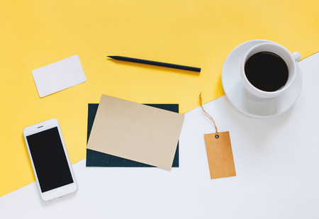 Creative flat lay photo of workspace desk with smartphone, coffee, tag and letter with copy space background, minimal styledの写真素材