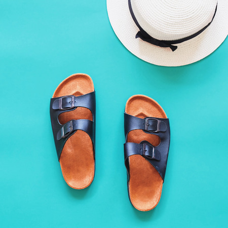 Leather sandals with panama hat in summertime concept on green backgroundの写真素材